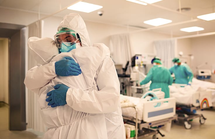 two medical workers embracing in PPE