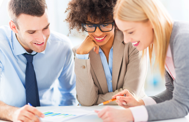 A group of three employees reviewing work material.