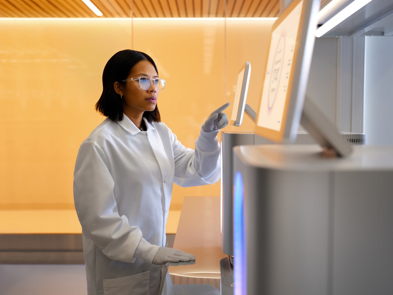 Back view of a female scientist examining a second 25B flow cell cartridge before inserting into a NovaSeq X drawer.