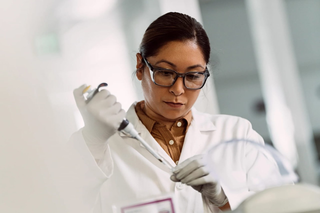 Female scientist holding a single pipette in one hand and a tube in the other.